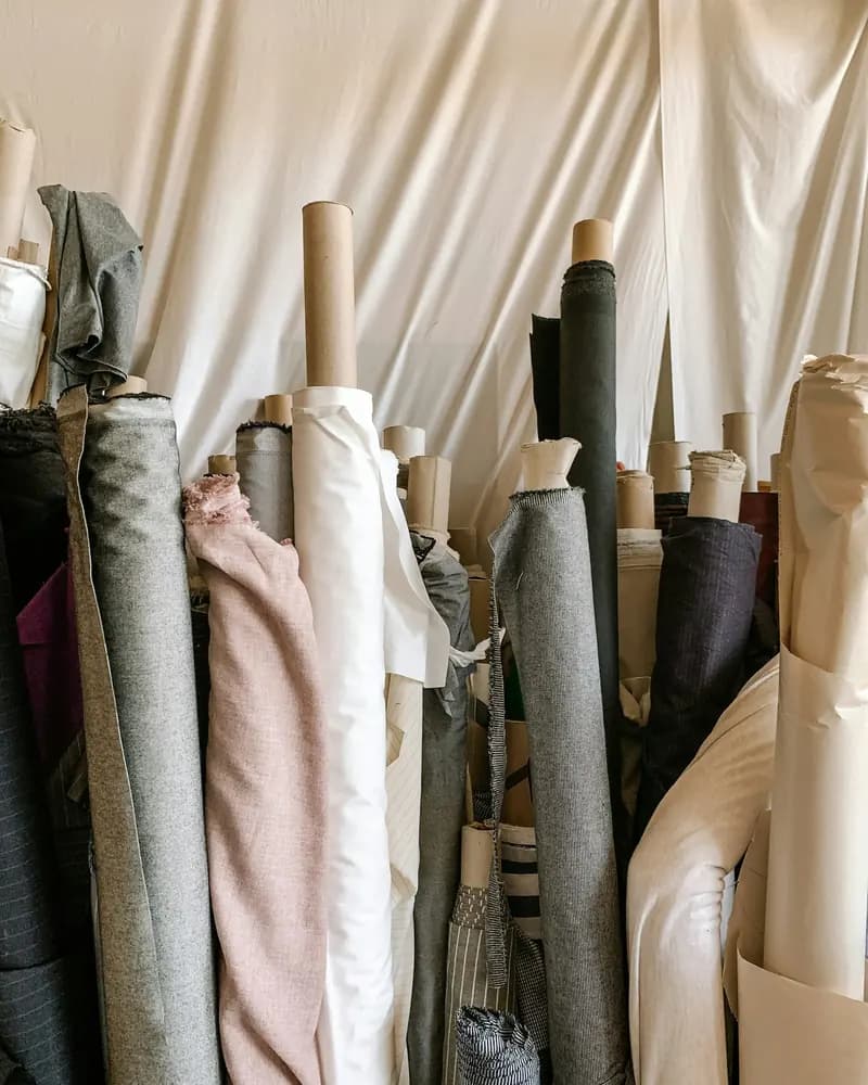 Bolts of linen and wool standing on end in a workroom