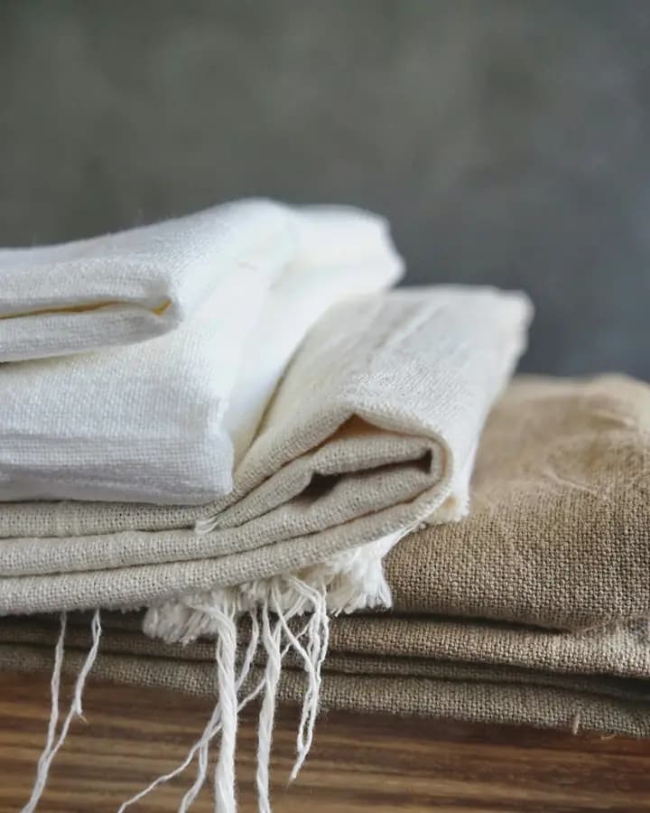 A stack of folded linen cloths with raw fringed edges
