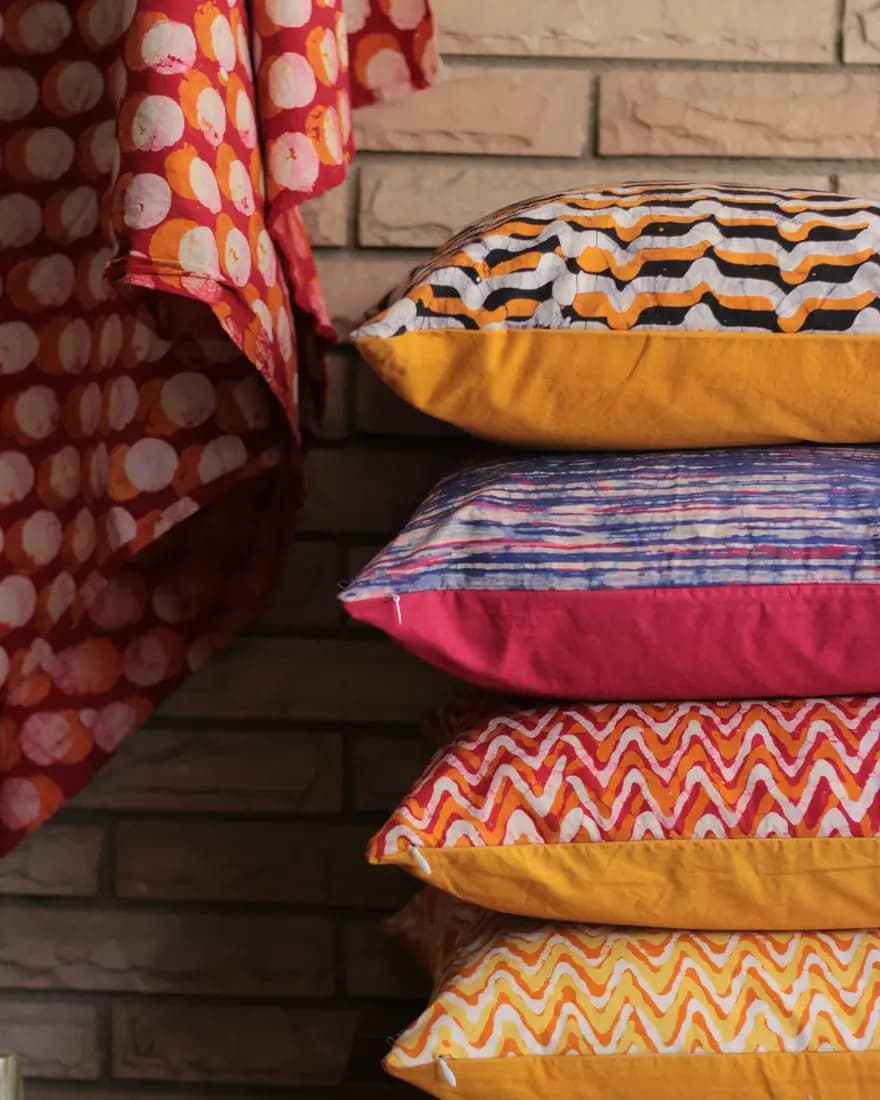 Block-printed cushions stacked against a brick wall