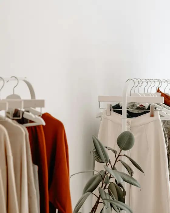 A rust-coloured knit and cream trousers hanging on a rail
