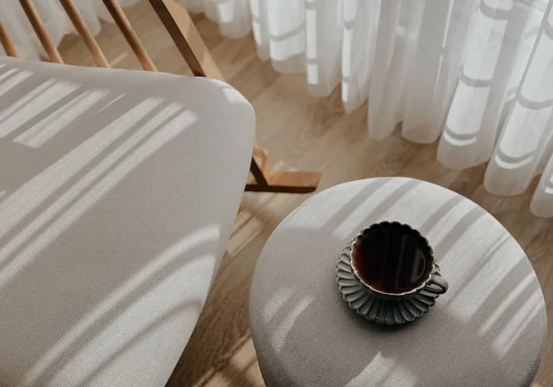 Morning light and curtain shadows across a low round table
